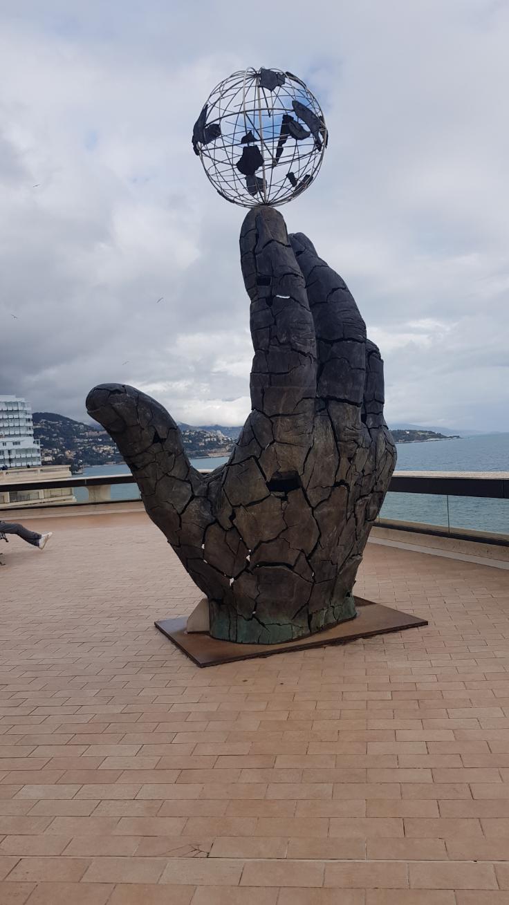 The Hand with globe on the index finger represents Strength Monaco, the second-smallest country on earth.
